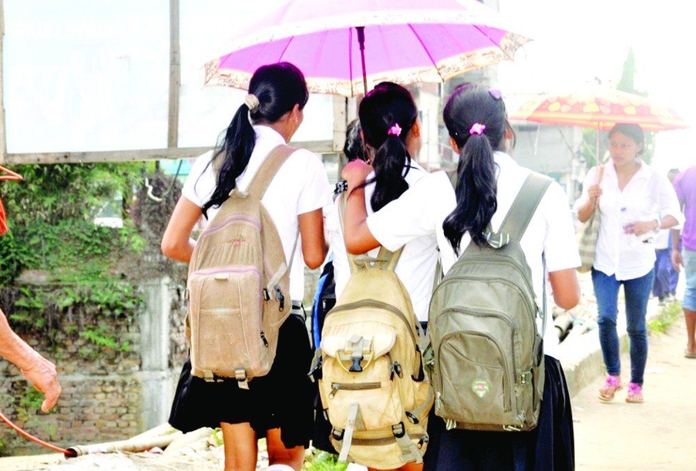 With heavy school bags slung over their shoulders, school girls walk back home from school. In most schools in Nagaland, young children are made to carry overly heavy school bags causing the risk of permanent back problems. (Morung photo)
